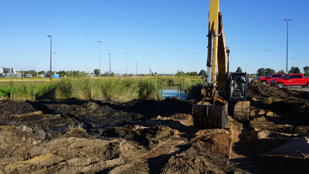 More excavation/demolition of existing stormwater pond edge for expansion and precision grading.
